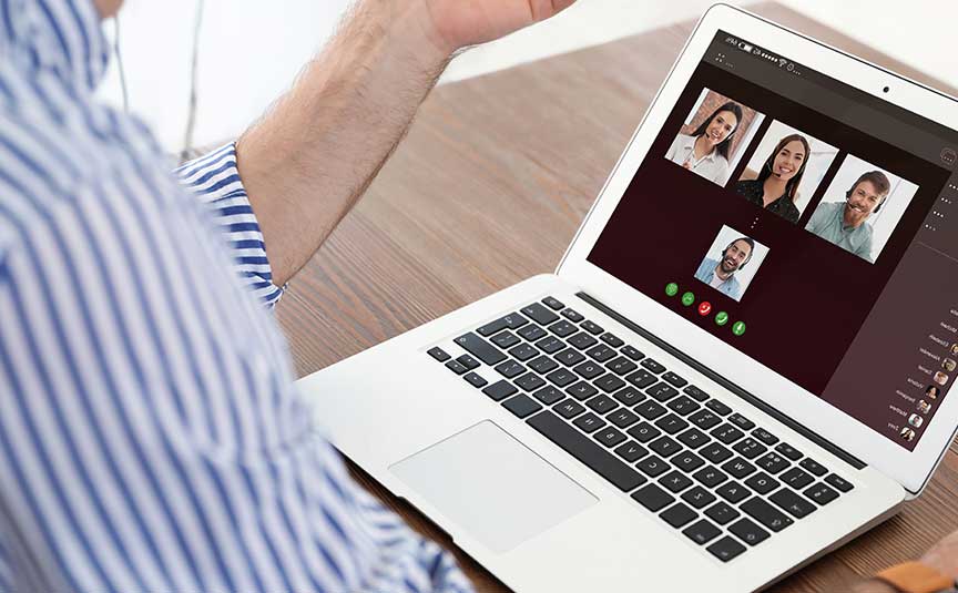 Man having video chat with colleagues at table in office